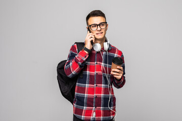 Wall Mural - Smiling student with bag holding books and talking on a phone isolated on gray background