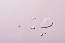 A Top View Closeup Of Multiple Water Drops On A Light Purple Background