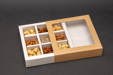 Wall Mural - The box on a dark background for nuts is divided into cashews, almonds, raisins and sunflower seeds, selective focus.