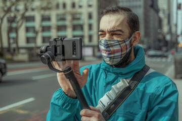 Wall Mural - Man using phone with stabilizer and taking pictures and live video in New York city. Vlog, video blogging, street photography concept.