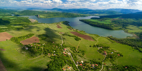 Wall Mural - An aerial shot of the green landscapes, fields and a river under the cloudy sky on a sunny day