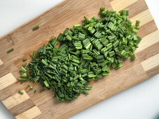 Wall Mural - A closeup shot of green onions slices on a wooden cut board