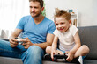 © fotofabrika - Father and his little son playing video games together at home