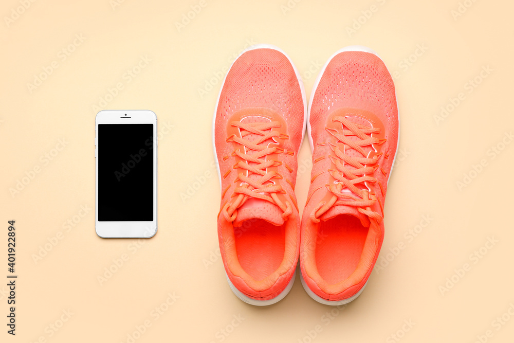 Sportive shoes and mobile phone on light background