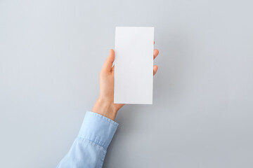 Female hand with blank paper on light background