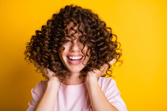 photo portrait of girl with curly hairstyle wearing t-shirt laughing touching hair isolated on brigh