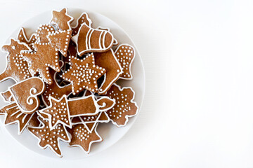 Christmas homemade gingerbread on a plate, handmade, various molds, top view on a white wooden table.