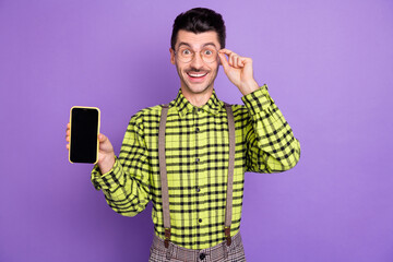 Poster - Photo portrait of man showing phone with blank space touching glasses isolated on vivid violet colored background