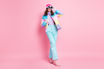 Wall Mural - Full length photo of pretty cute woman skier dressed colorful windbreaker walking arm eyeglasses isolated pink color background