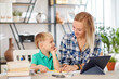© DragonImages - Young smiling mother helping little son to prepare for online classes