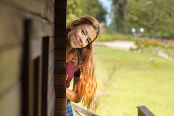 Poster - A pretty woman posing near the wooden house on a sunny day