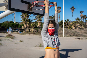 Poster - A Caucasian female with face mask hanging on a basketball hoop