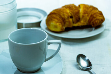 Canvas Print - A top view closeup of a croissant on a white plate next to a container with powdered sugar and coffee