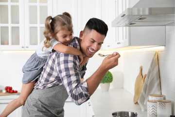 Little girl with her father cooking together in modern kitchen