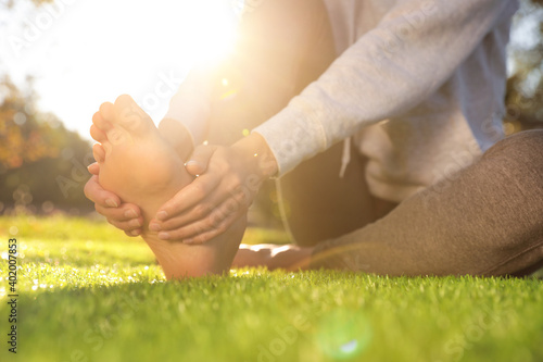 Foto Young woman sitting barefoot on fresh green grass outdoors, closeup