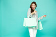 © comzeal - Young Asian woman holding light green shopping bags isolated on green background