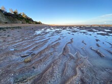 Pett Level Beach At Sunset. With Pool Of Sea Ocean Water And Rocks In Foreground. Winchelsea Beach Meets The Cliffs A Petrified Forest Visible At Low Tide, On The South Coast Of England East Sussex UK