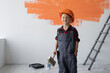 © Andrii Lysenko - a boy dressed in overalls stands in the room holding a paintbrush in his hands. Home renovation concept.