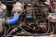 old dirty car engine with numerous modifications under the hood