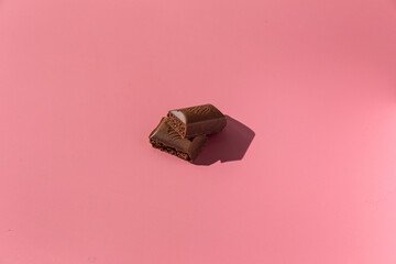 pieces of chocolate on a pink background with hard light