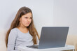 © QKon Studio - Emotional portrait of attractive cute girl 6-7 old she is tired in a bad mood sitting using laptop on distance learning