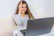 © QKon Studio - Portrait of attractive cute happy smiling girl 6-7 old sitting using laptop indoor white background distance learning