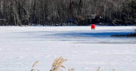 frozen winter lake with red ice fishing hut