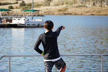 Wall Mural - Young sporty Asian boy looking at the view on a wood pier at the Lake. Teenager concept