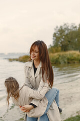 Wall Mural - Fashionable mother with daughter. People walks outside. Woman in a brown coat.