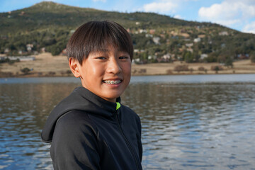 Wall Mural - Portrait of young sporty Asian boy by the Lake. Teenager concept