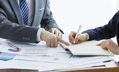 two businessmen in elegant suits at a business meeting taking notes in the office