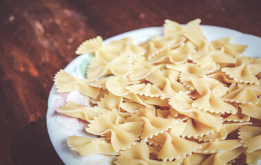 Wall Mural - A closeup of Italian farfalle pasta in a white plate on a wooden table