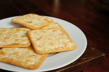 Poster - A top view closeup of healthy salted crackers on a white plate on a wooden table