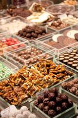 Canvas Print - A top view closeup of walnuts and other chocolate sweets in white plastic containers at the store