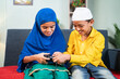 © WESTOCK - Muslim brother snatching gamepad from his sister to play video game at home - Concept of childhood sibling fighting
