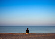 © Evgeny Leontiev - A young man meditates on the beach during sunset.