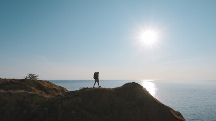 Wall Mural - the tourist walking to the mountain edge on the seascape background