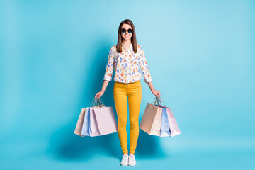 Photo of lovely lady hold mall packets wear sunglass geometry print shirt yellow trousers isolated blue color background