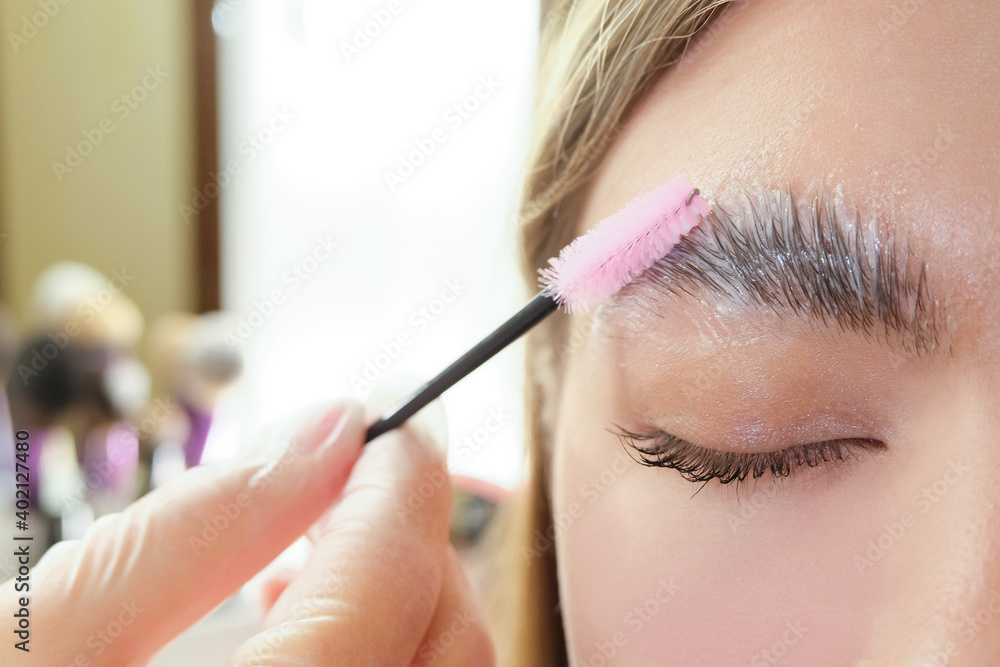 Beautiful young woman got correction of eyebrows in a beauty salon - obrazy, fototapety, plakaty 
