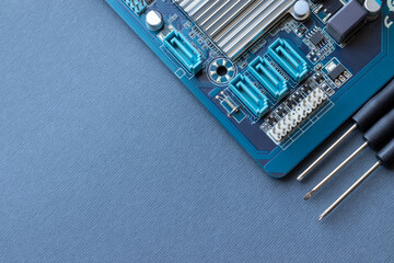 Computer motherboard and three small screwdrivers on a gray paper background with copy space. Computer equipment repair, assembly and upgrade of system units