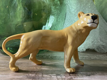A Yellow Porcelain Lioness Figurine On Green Glass Background