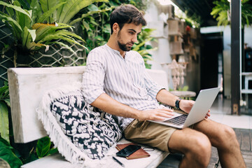 Wall Mural - Focused man with laptop on bench in garden