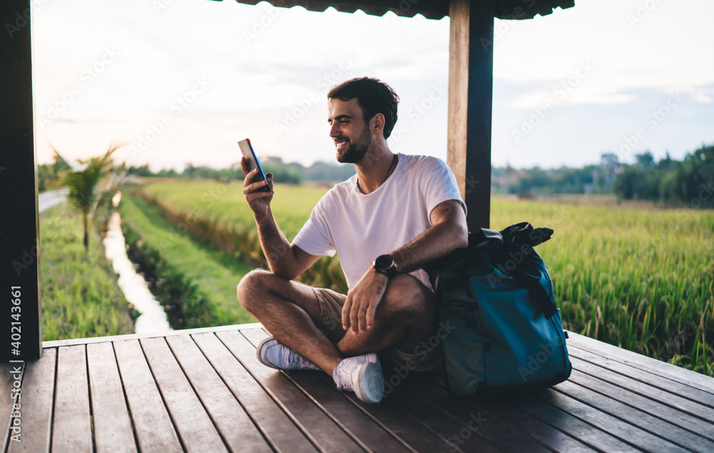 Cheerful male traveler using cellphone in tropical countryside - obrazy, fototapety, plakaty 