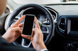 © LIGHTFIELD STUDIOS - Cropped view of man holding smartphone with blank screen near steering wheel in car on blurred background.