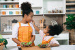 © chachamp - Happy sister black skin with salad on plate in kitchen