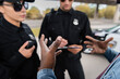 © LIGHTFIELD STUDIOS - african american man victim gesturing near police officers on blurred background outdoors.