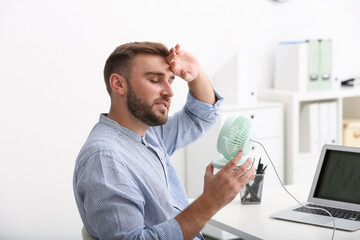 Wall Mural - Man enjoying air flow from fan at workplace