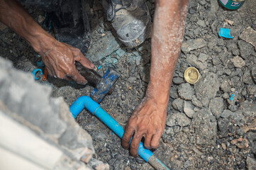 Plumber is hammering the PVC pipe installation in the bathroom