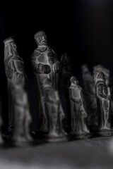 Wall Mural - A portrait of the black stone sculptured army on a stone chessboard. They are setup for the beginning of the strategic match.