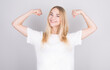 © MP Studio - Young pretty blonde woman feeling happy, satisfied and powerful, flexing fit and muscular biceps, looking strong after the gym against white wall